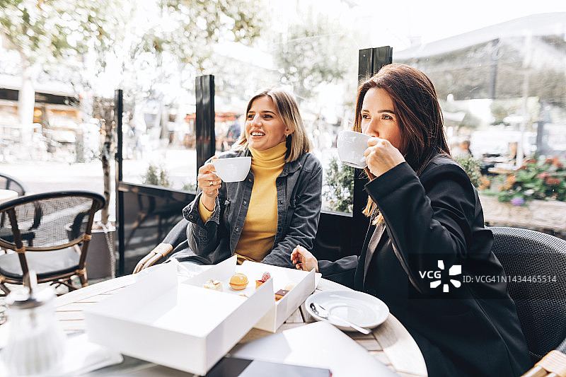 两个女朋友在一家街头咖啡馆见面喝咖啡。图片素材