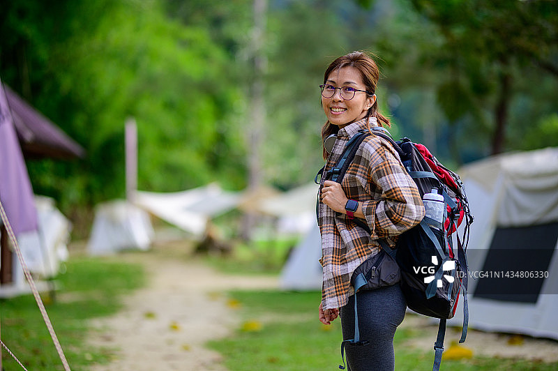 快乐的亚洲华人女性背包客沿着营地徒步路线，欣赏热带雨林。看相机图片素材