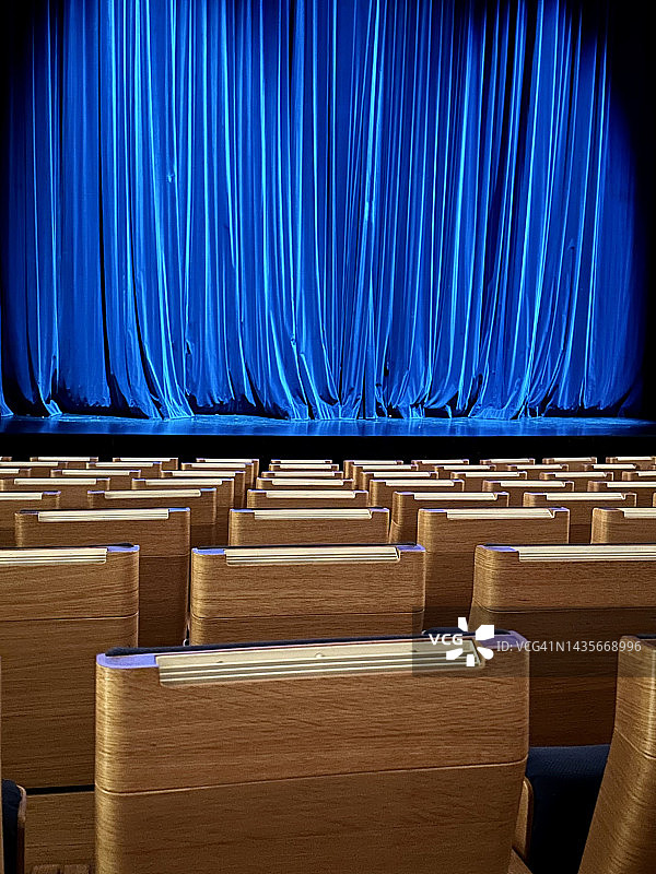 空荡荡的剧院座位和拉上的蓝色舞台幕布图片素材
