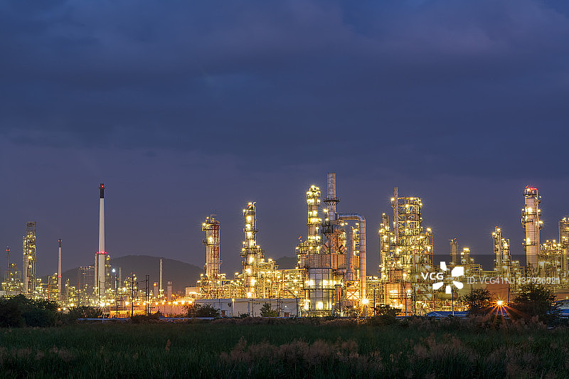 在美丽的黄昏带油管和油罐的炼油厂，有油罐储存的炼油厂，石化厂，化工厂在日落时分图片素材