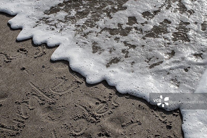 高角度拍摄的海水到达海岸冲刷沙滩上的文字图片素材