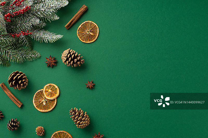 圣诞装饰概念。俯视图照片干橙片八角肉桂棒松果槲寄生浆果和云杉树枝在白霜孤立的绿色背景与空白图片素材