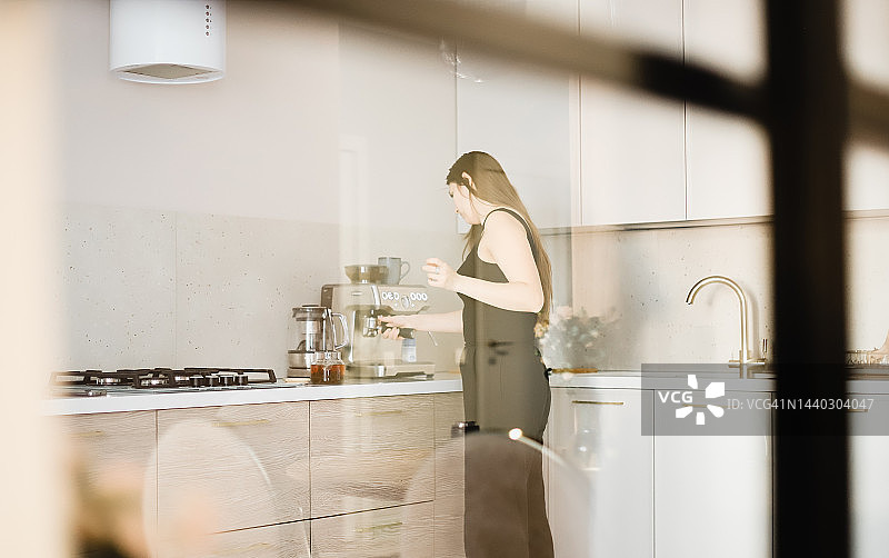 厨房里的女孩用咖啡机准备茶和咖啡图片素材