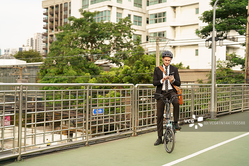 商人骑着自行车在城市里旅行时用电话交流图片素材