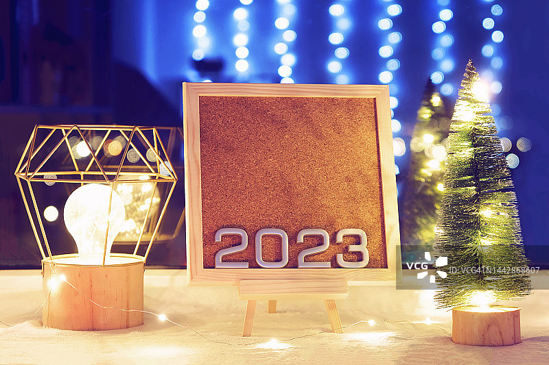 2023年新年的数字在圣诞树和彩灯旁边的漂亮画架上。2023年新年和圣诞节酒店预订的折扣和促销活动。2023年销售。生产日历2023。图片素材