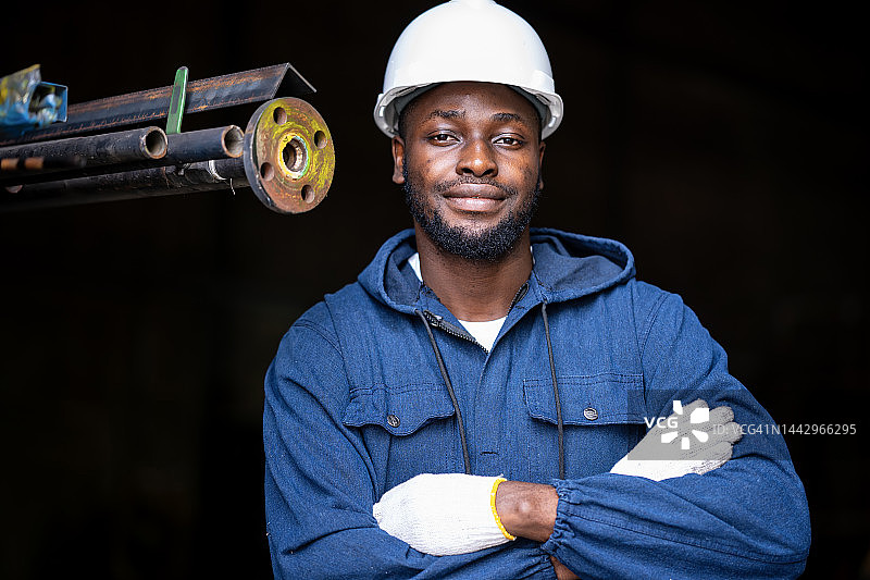 用工业工人技能推动企业和工业增长。自信的非裔美国工业工人站在金属工业的画像。图片素材