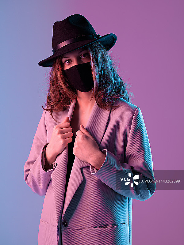 时髦的女人戴着紫色背景的保护面具图片素材