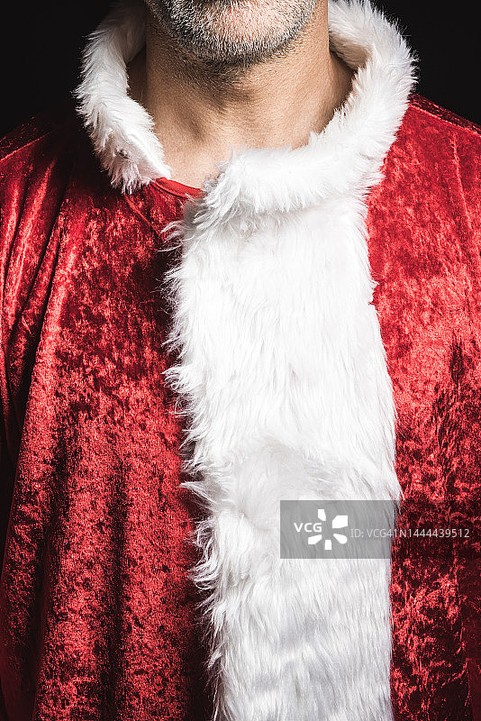 一个身份不明的人的胸部细节，打扮成圣诞老人。圣诞节和庆祝的概念。图片素材