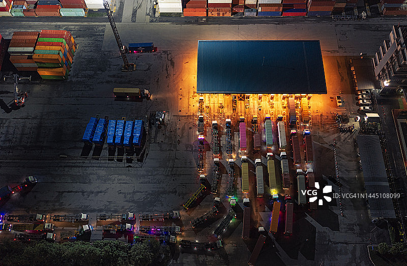 黄昏时分，集装箱卡车在码头商埠排队进入码头，为集装箱货船卸货，业务物流进出口或货运。图片素材