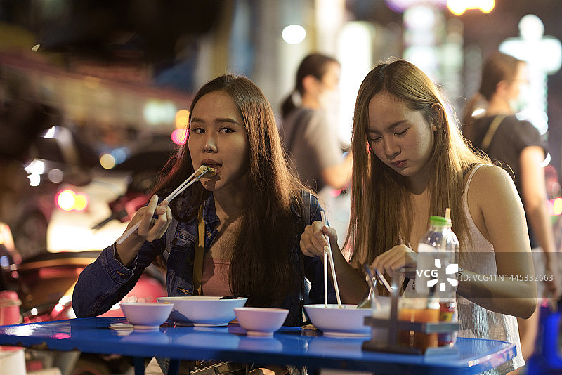 女游客在夜市吃面食图片素材