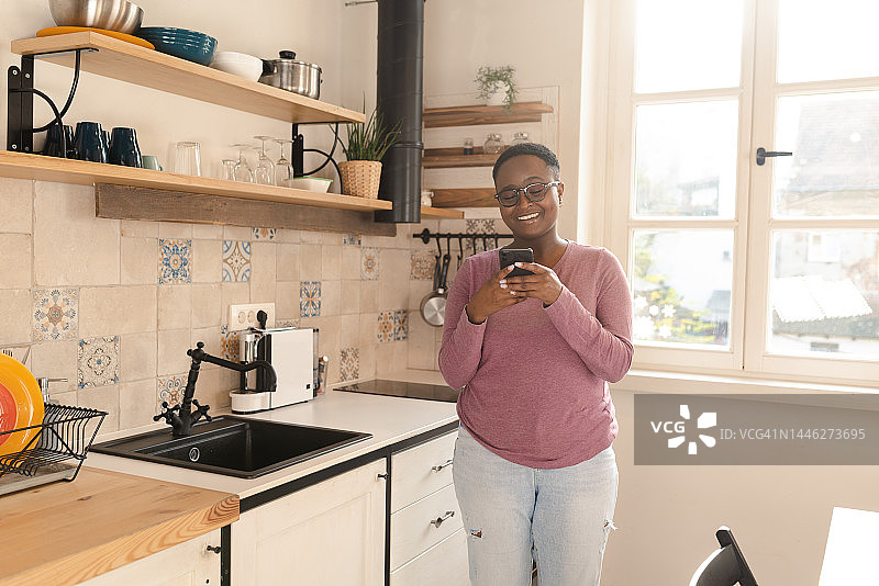 一个快乐的非裔美国年轻女性在她的智能手机上发短信的画像图片素材