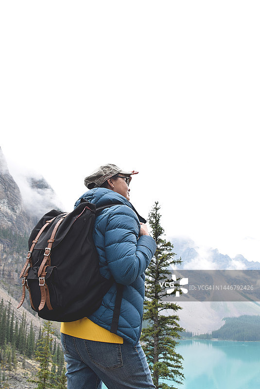 背着背包的女人看着绿松石色的湖和山图片素材