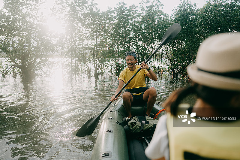 一名男子划着竹筏穿过红树河，日本，Iriomote岛图片素材