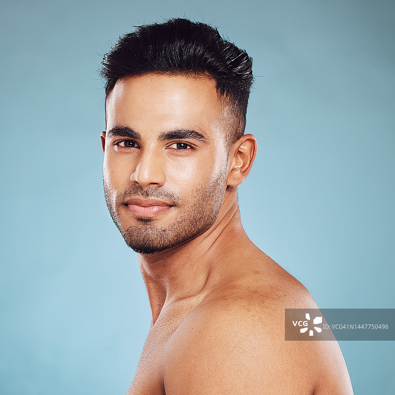 健康护肤和一个男人的肖像，裸露上身，健康的皮肤和自然发光后排毒面部和微笑在印度。男性身体护理，健身和自爱的工作室与蓝色背景。图片素材
