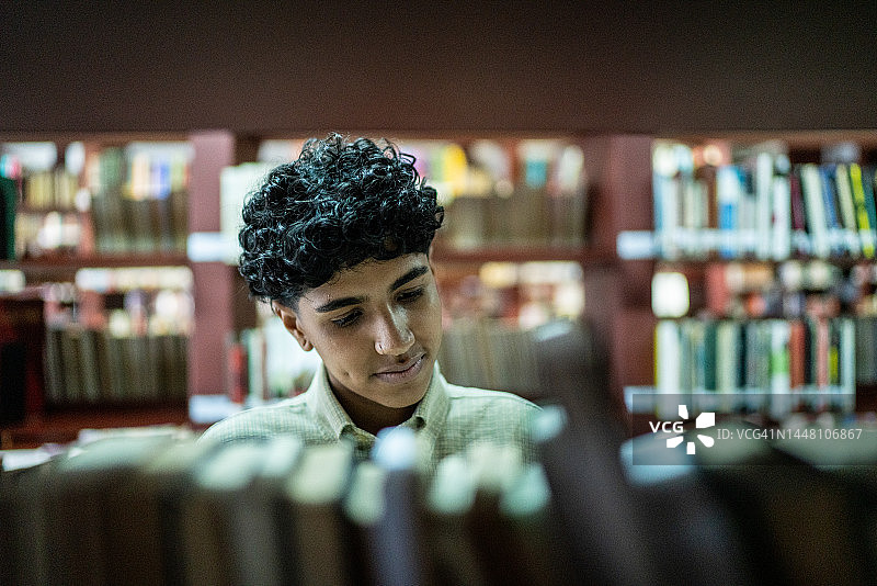 一名年轻女子在图书馆的书架上找书图片素材
