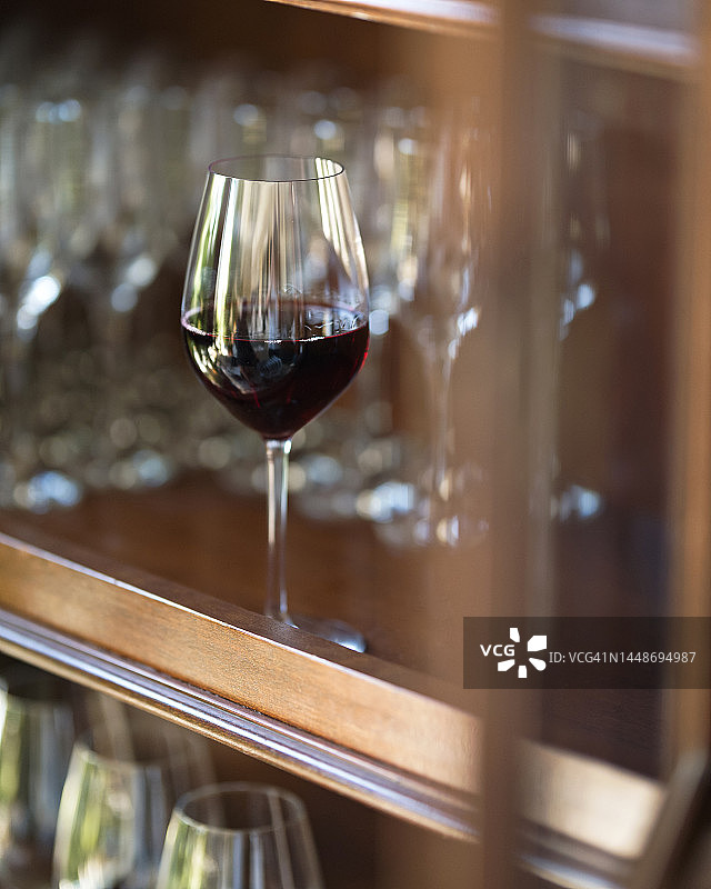 木架上放一杯红酒。酒精饮料。意大利葡萄酒。品酒。背景是模糊的玻璃眼镜。软的焦点。本空间图片素材