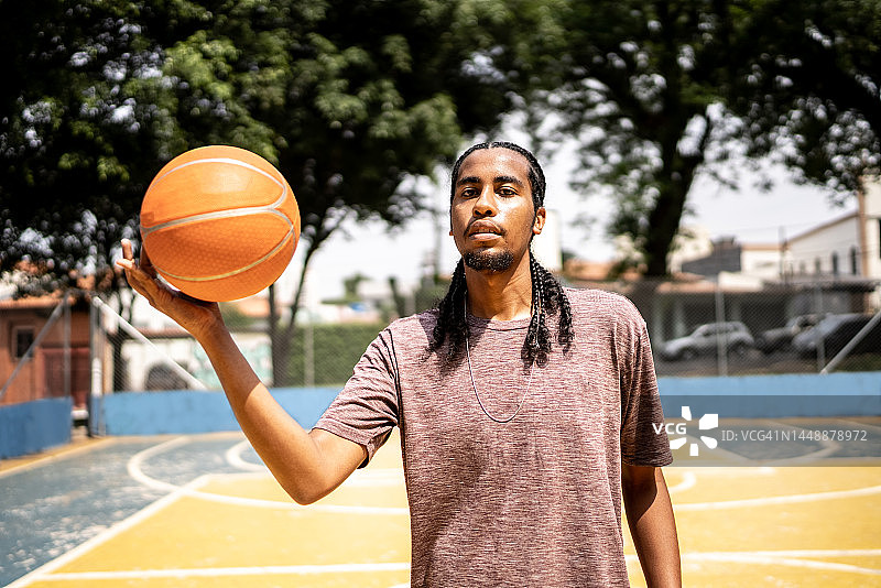 一个年轻人在运动场上抱着一个篮球的肖像图片素材