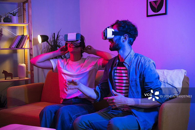 一对年轻夫妇使用虚拟现实头盔和玩得很开心的肖像图片素材