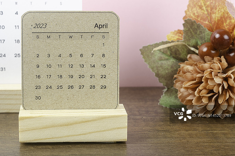 2023日历桌:4月是组织者计划和截止日期的月份，用手工制作的木桌背景。图片素材