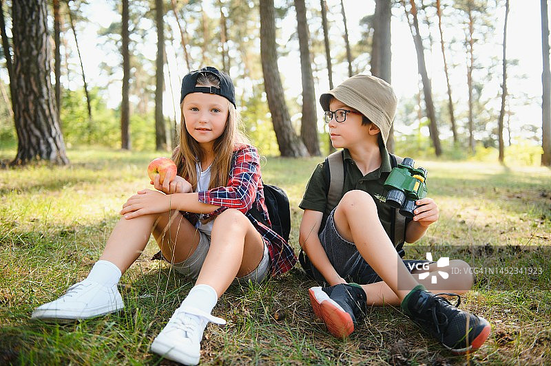 男孩和女孩背着背包在阳光明媚的森林路上徒步旅行图片素材