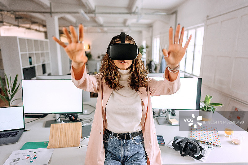 年轻漂亮的女人在现代办公室使用VR眼镜图片素材