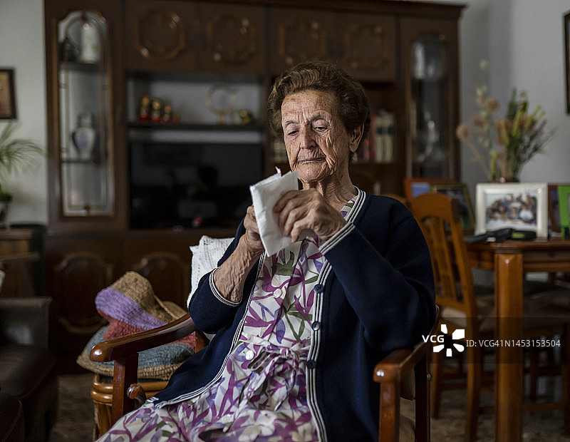 老妇人坐在扶手椅上，掏出手帕，准备在家里安静地度过一个晚上。图片素材