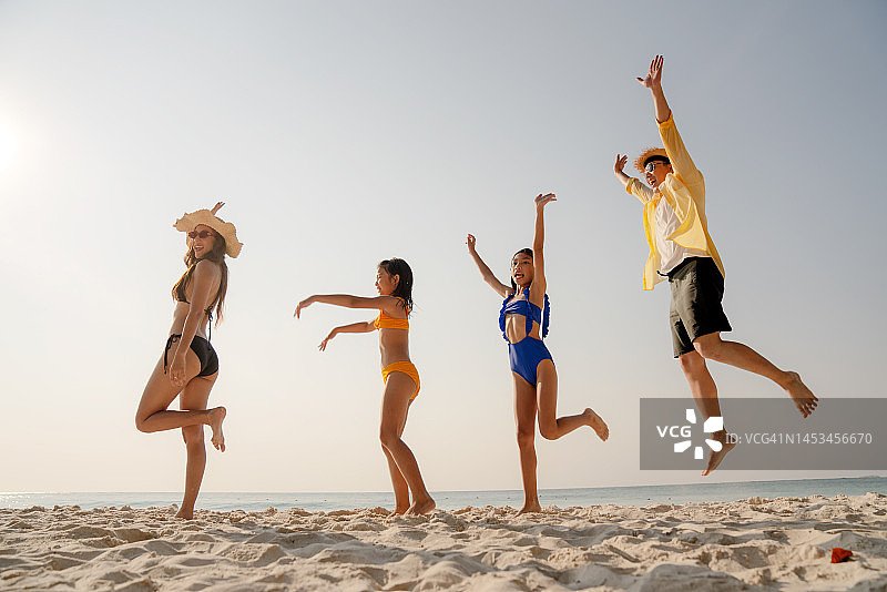 亚洲家庭假期和休闲概念。假日，快乐的亚洲家庭一起在海滩上蹦蹦跳跳。图片素材
