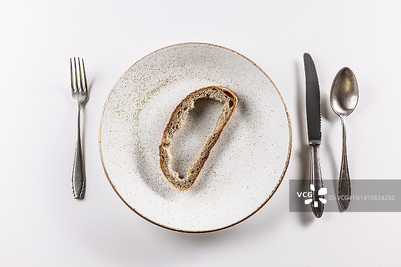 面包皮放在盘子上，餐具放在白色背景上。图片素材