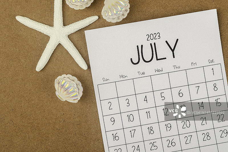日历桌2023:7月是组织者用海星和贝类在棕色纸背景下进行计划和截止日期的月份。图片素材