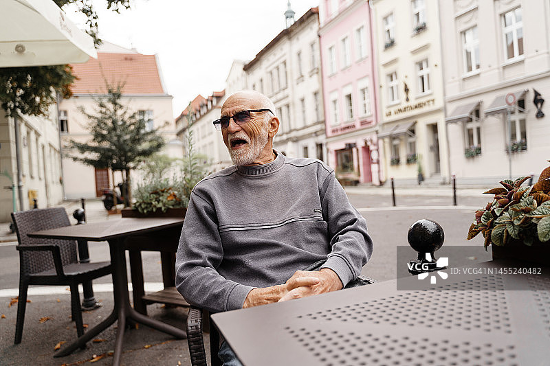 快乐的老人坐在欧洲的咖啡馆外图片素材