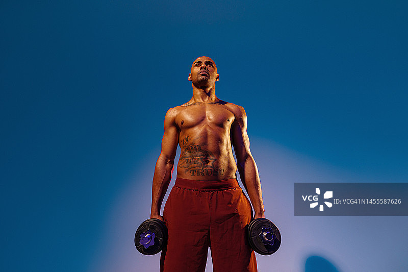 肌肉男子在工作室背景做举重哑铃锻炼。力量和动力图片素材