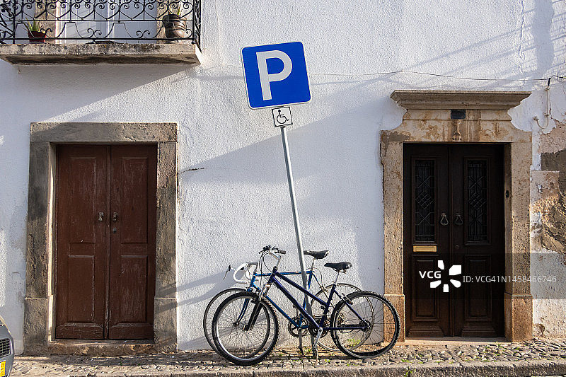 葡萄牙阿尔加维，残疾人停车区，两辆自行车靠在停车标志上图片素材