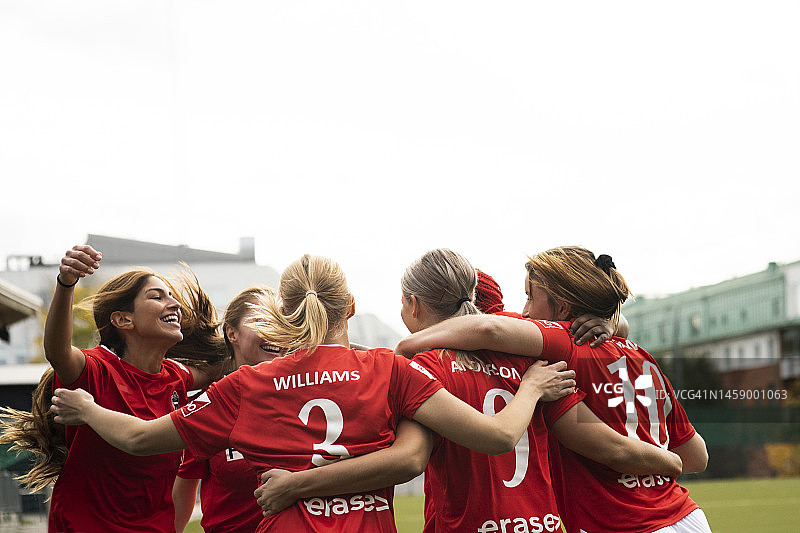 兴奋的女足队员们在体育场里挤在一起庆祝胜利图片素材