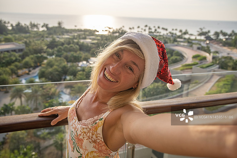 一名女子在酒店房间庆祝圣诞节，她在阳台上自拍图片素材