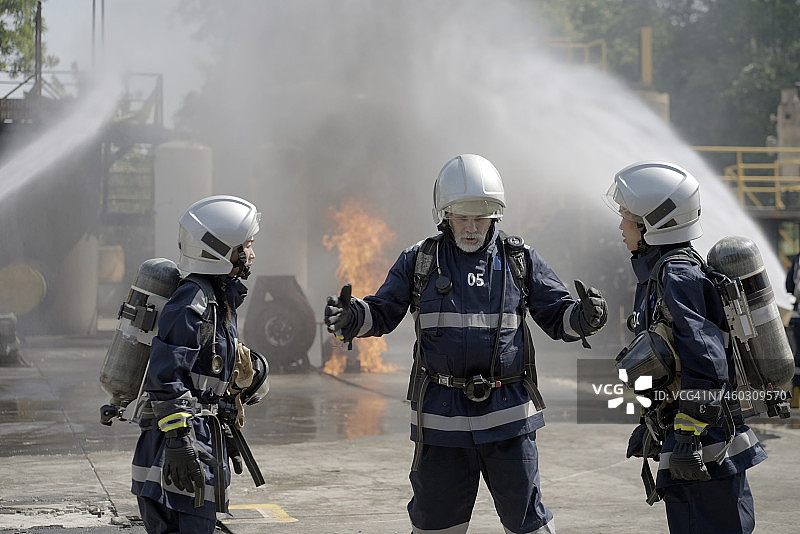 消防队员训练，消防队员使用水和灭火器灭火。图片素材