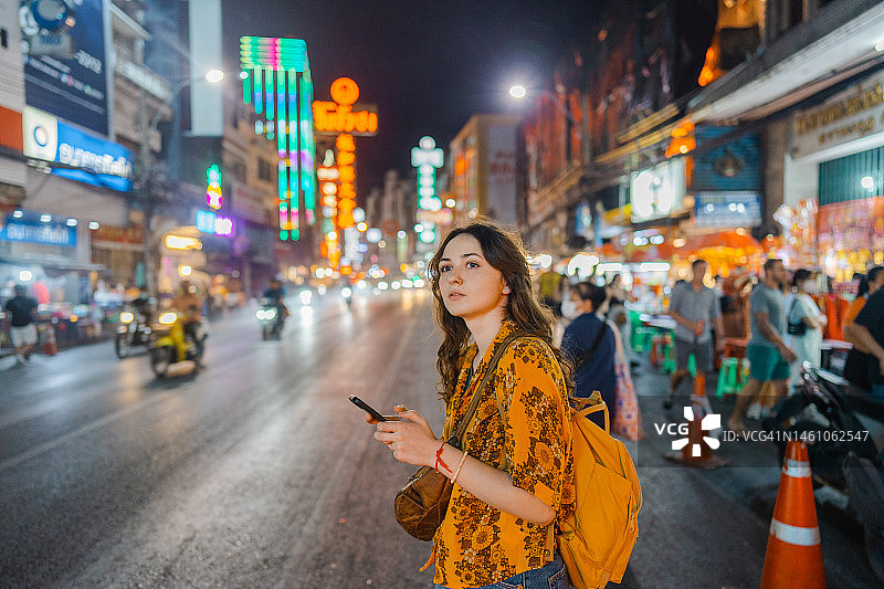 一名女子拿着智能手机站在曼谷唐人街图片素材