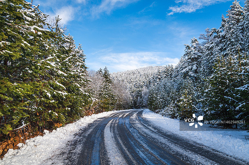 在一个阳光明媚的日子里，山路上的积雪和树木都被清除了图片素材