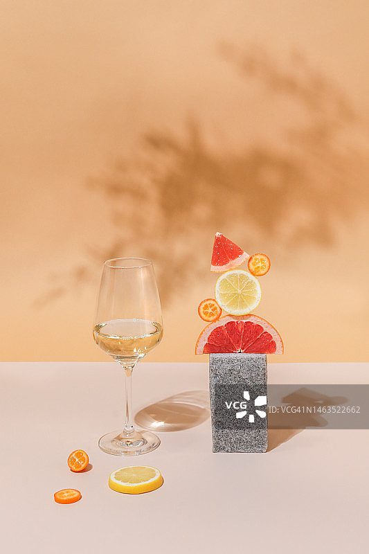 白色葡萄酒杯，以明亮柔和的颜色为背景，点缀柑橘类水果图片素材