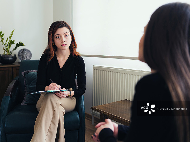 心理治疗师在治疗过程中倾听女性来访者。图片素材