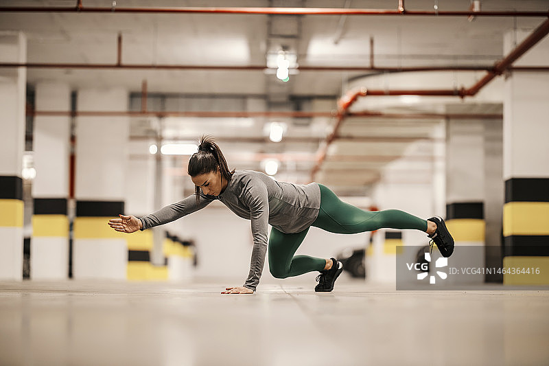 一个强壮的女运动员正在地下车库做力量训练。图片素材