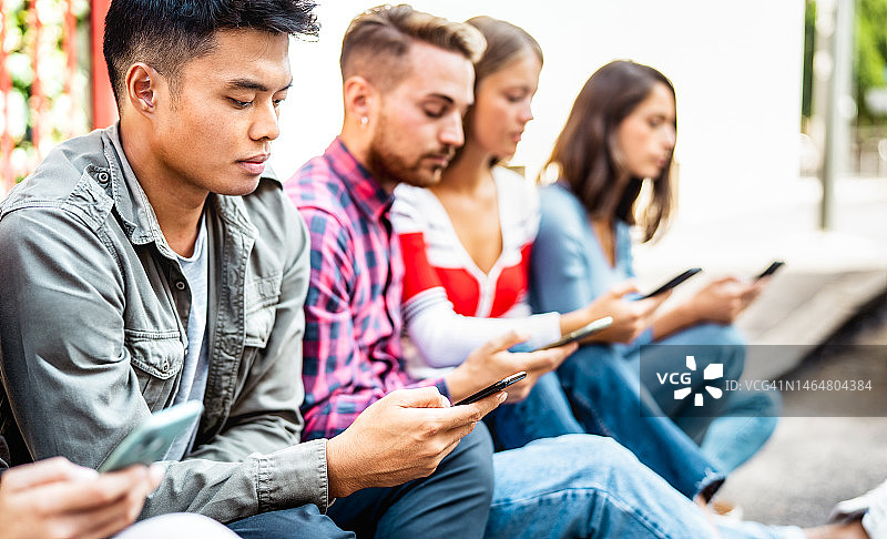 无聊的人使用智能手机坐在大学校园-年轻的朋友在移动智能手机上观看病毒视频-技术生活概念与始终连接的学生-明亮的过滤器图片素材