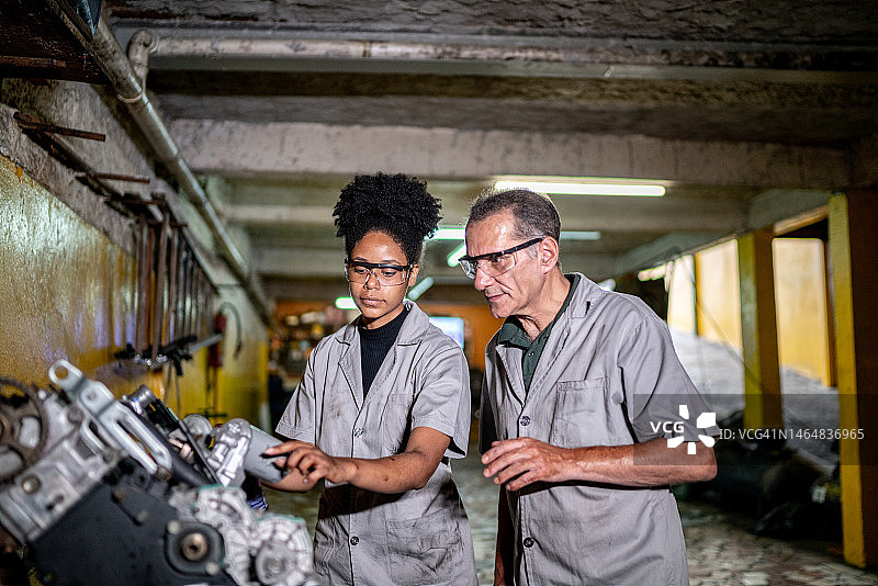 汽车修理工在修理厂教他的助手图片素材