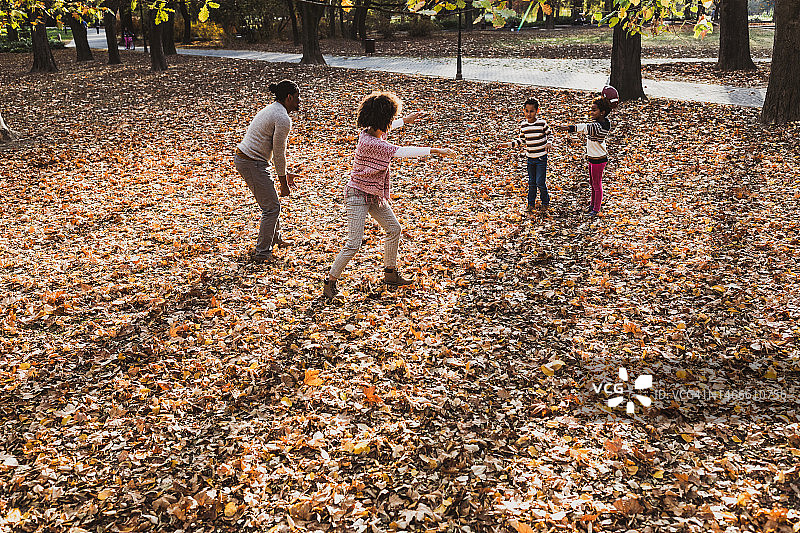 顽皮的黑人家庭在公园里玩橄榄球。图片素材