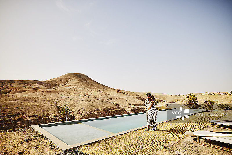 摩洛哥沙漠营地，一对情侣在泳池边拥抱微笑图片素材