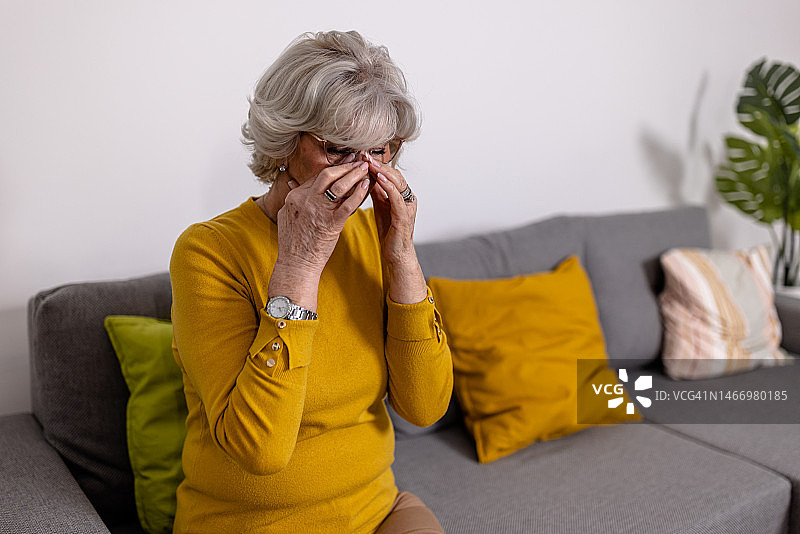 一位患有慢性鼻窦炎的孤独老年妇女在与头部难以忍受的疼痛作斗争时感到绝望。图片素材