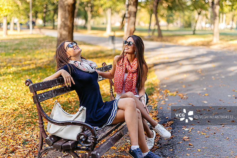 两个女性朋友在公园长椅上聊天图片素材