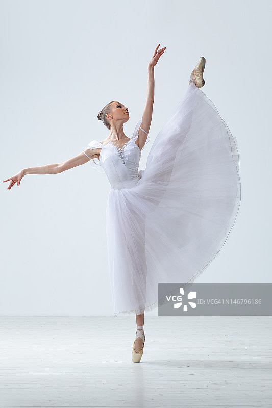 女舞者穿着白色的裙子，一条腿直举在空中图片素材