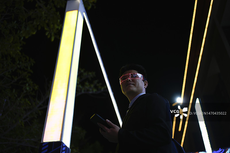 一名戴着智能眼镜的男子在夜间使用手机图片素材