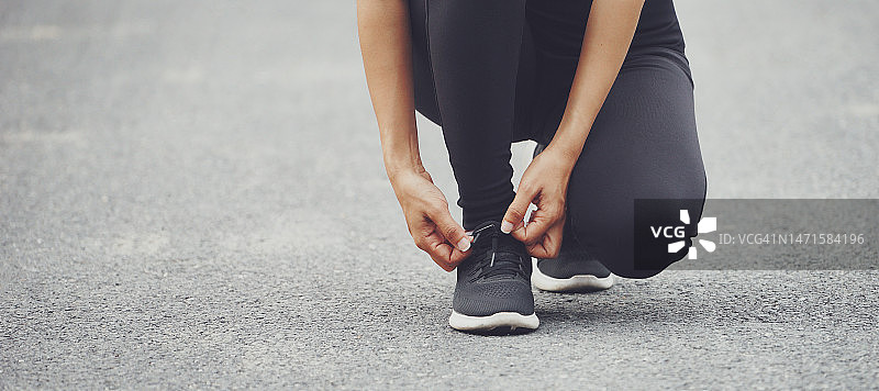 穿跑鞋的女子为秋天在森林公园跑步系鞋带。跑步者试穿跑鞋，准备跑步。慢跑女孩运动动力健康健身。图片素材