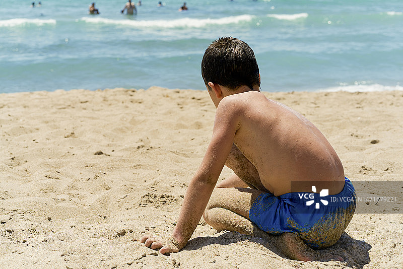 小男孩在沙滩上享受阳光明媚的一天。图片素材
